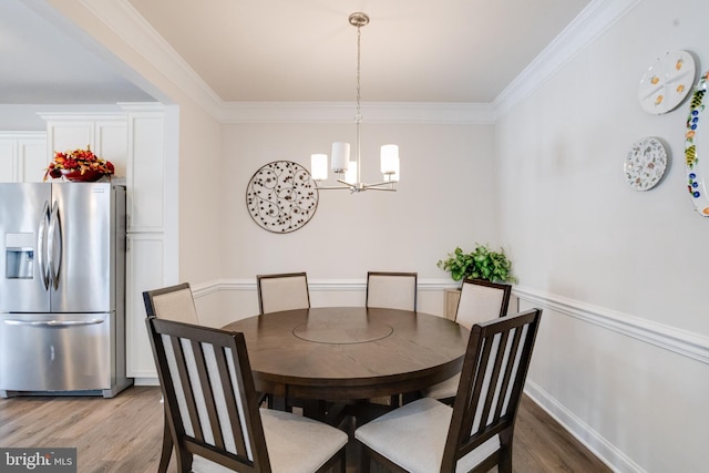 dining room with crown molding, a notable chandelier, and light wood-style floors