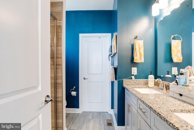 full bathroom with wood finished floors, a sink, visible vents, baseboards, and double vanity