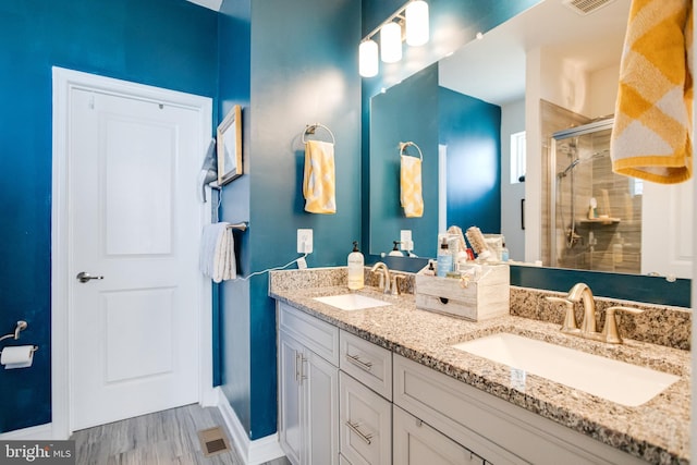 full bath featuring double vanity, a stall shower, a sink, and visible vents