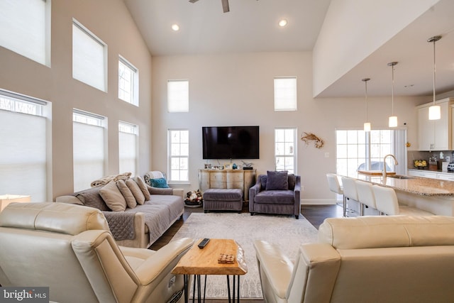 living area with high vaulted ceiling, a wealth of natural light, dark wood-style flooring, and recessed lighting