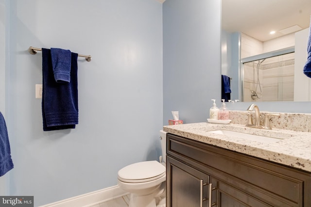 bathroom with a stall shower, baseboards, vanity, and toilet