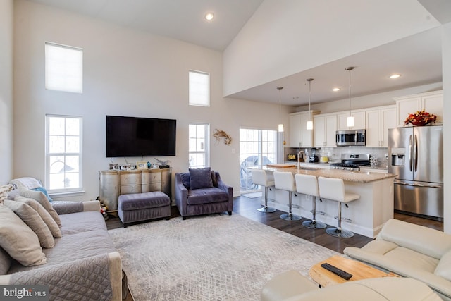 living area with high vaulted ceiling, dark wood-style flooring, and recessed lighting