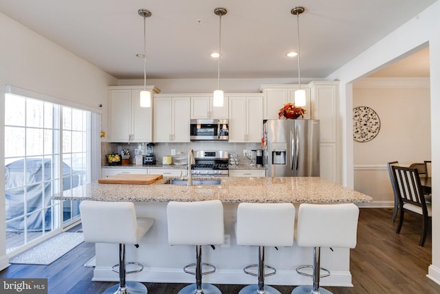 kitchen with tasteful backsplash, an island with sink, dark wood-style floors, appliances with stainless steel finishes, and a sink