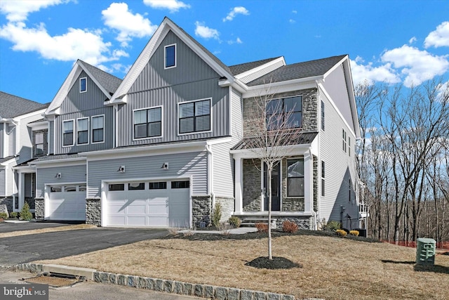 view of front facade with board and batten siding, stone siding, driveway, and an attached garage