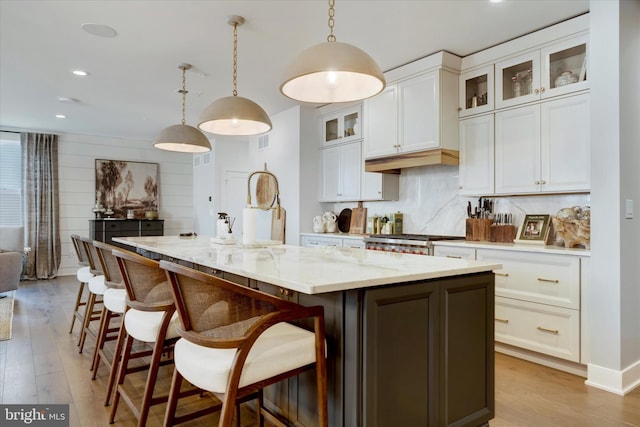 kitchen with tasteful backsplash, a large island, light wood finished floors, and stove