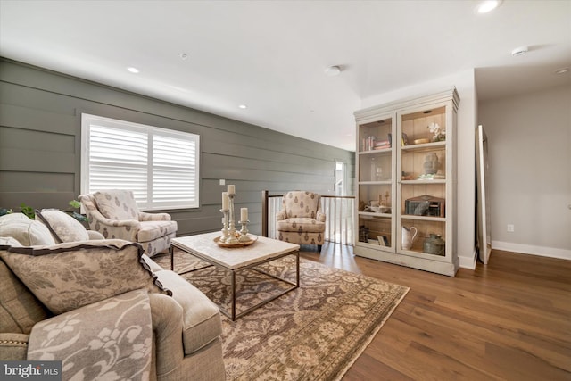 living room featuring recessed lighting, wooden walls, baseboards, and wood finished floors