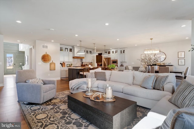 living room featuring dark wood-type flooring, recessed lighting, visible vents, and a notable chandelier