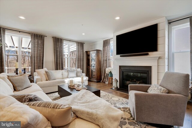 living room featuring a fireplace with flush hearth, recessed lighting, and wood finished floors