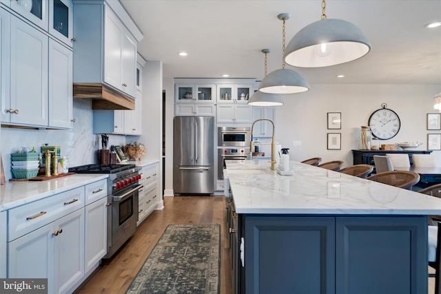 kitchen with recessed lighting, decorative light fixtures, dark wood-style flooring, appliances with stainless steel finishes, and a center island with sink