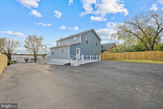 back of house with aphalt driveway and fence