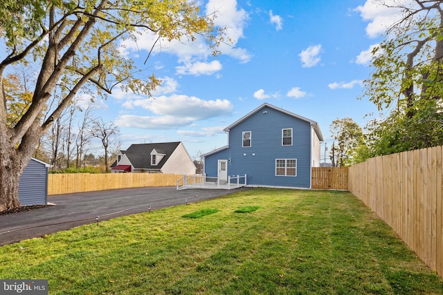 rear view of house with a fenced backyard and a lawn