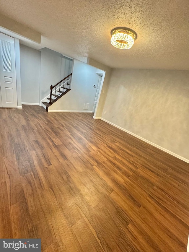 interior space with a textured ceiling, stairway, baseboards, and wood finished floors