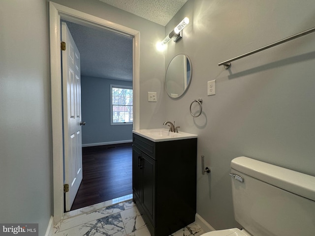 bathroom featuring marble finish floor, toilet, a textured ceiling, and baseboards