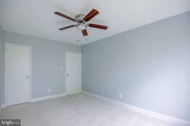 empty room featuring light carpet, baseboards, and a ceiling fan