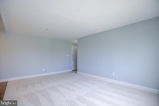 unfurnished room with light carpet and baseboards