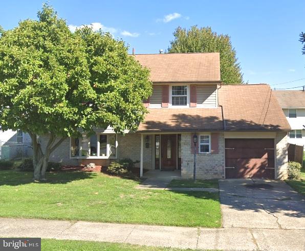 view of front of property featuring an attached garage, brick siding, concrete driveway, and a front yard