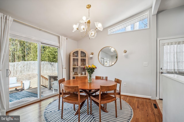 dining area featuring vaulted ceiling, wood finished floors, a wealth of natural light, and a chandelier