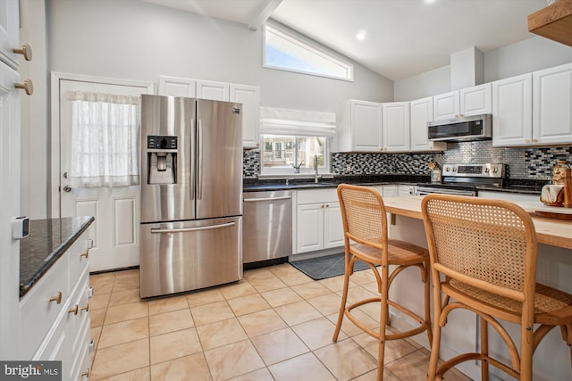 kitchen with decorative backsplash, light tile patterned floors, white cabinetry, and appliances with stainless steel finishes