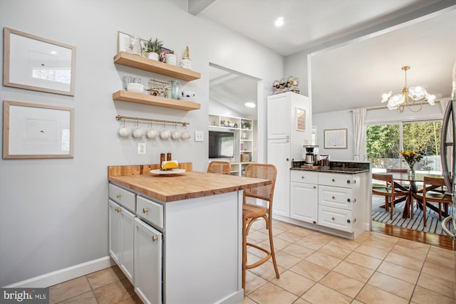 kitchen with wooden counters, a peninsula, a chandelier, and white cabinetry