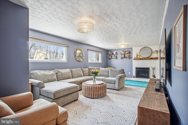 living room featuring a brick fireplace, a textured ceiling, and baseboards