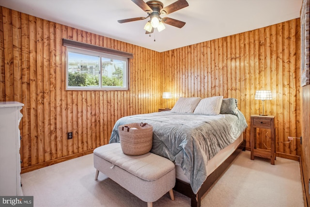 carpeted bedroom with wooden walls, a ceiling fan, and baseboards