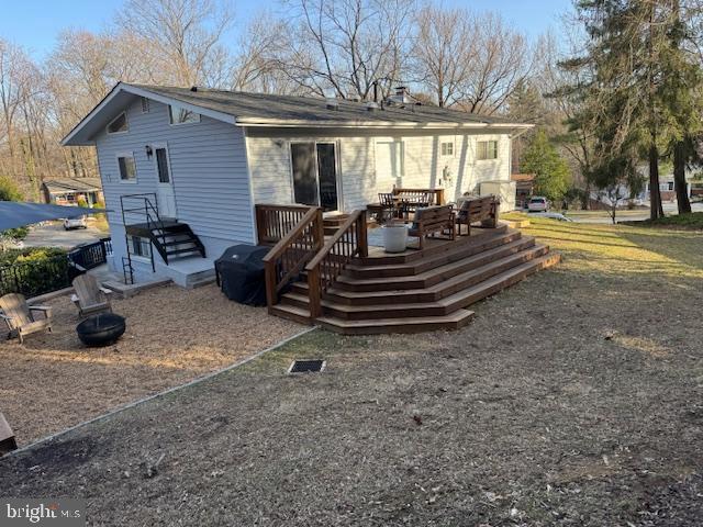 rear view of property featuring a wooden deck and an outdoor fire pit