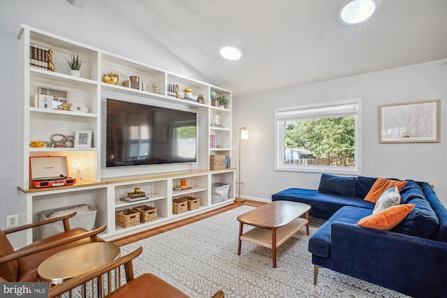 living area featuring vaulted ceiling, built in shelves, and wood finished floors