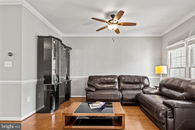 living area featuring ceiling fan, crown molding, baseboards, and wood finished floors