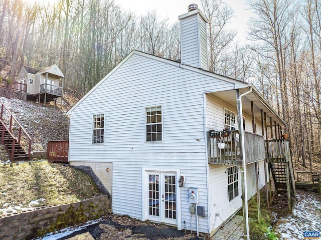 view of property exterior featuring stairway, french doors, a chimney, and a wooden deck