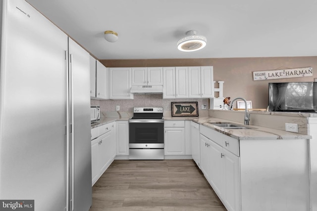 kitchen with under cabinet range hood, stainless steel appliances, a peninsula, a sink, and light wood-style floors