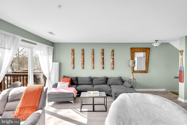 living room with baseboards, visible vents, and wood finished floors