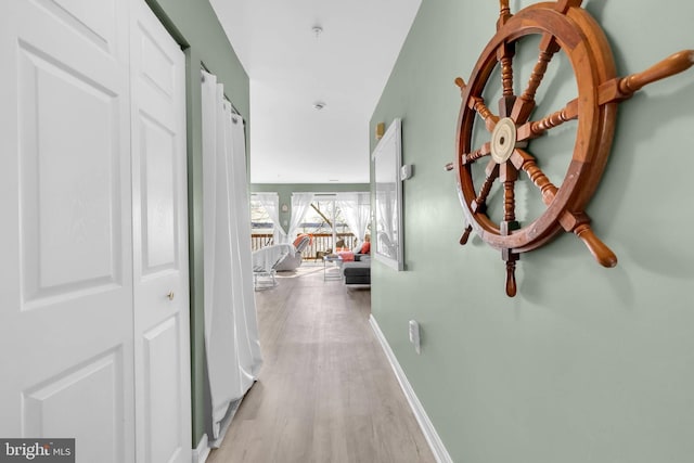 hallway featuring light wood-type flooring and baseboards