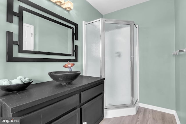 bathroom with a stall shower, baseboards, wood finished floors, and vanity