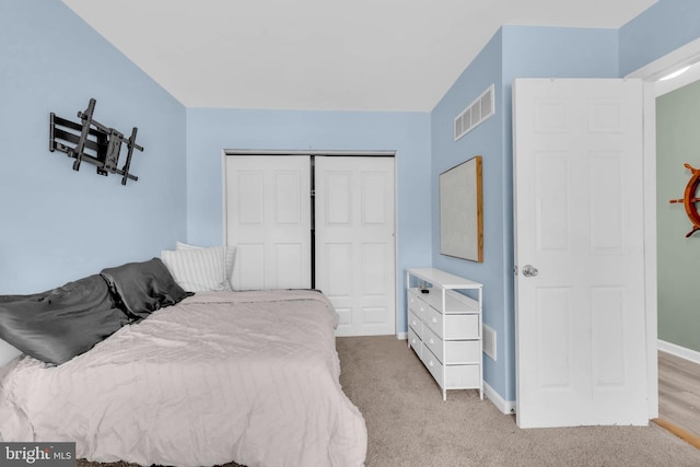 bedroom with a closet, visible vents, light carpet, and baseboards