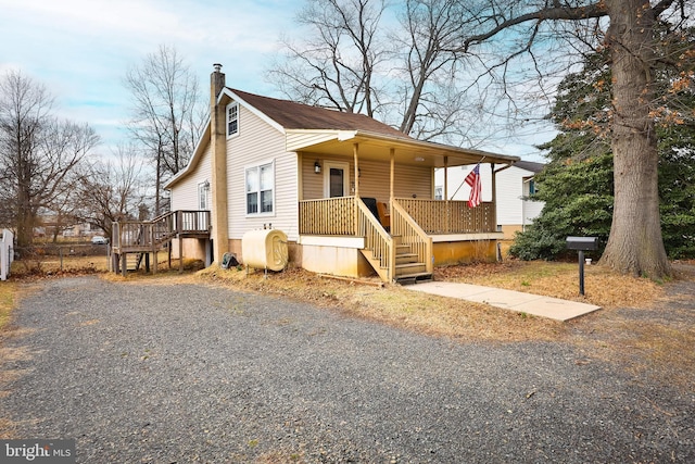 view of front of home with heating fuel, a chimney, and covered porch