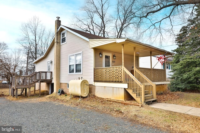 view of side of property featuring heating fuel, stairs, a chimney, and covered porch