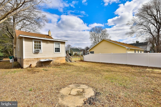 view of side of home featuring a lawn, a chimney, fence, and cooling unit