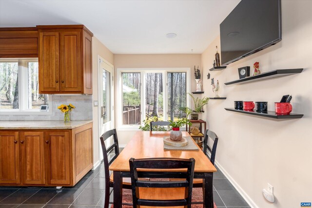 dining space featuring baseboards, dark tile patterned floors, and a healthy amount of sunlight