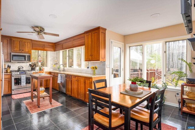 kitchen with stainless steel appliances, a sink, light countertops, decorative backsplash, and brown cabinetry