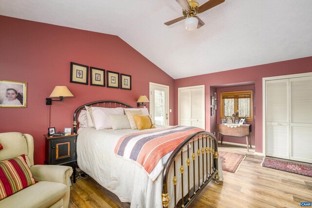 bedroom featuring vaulted ceiling, light wood-type flooring, a ceiling fan, and multiple closets