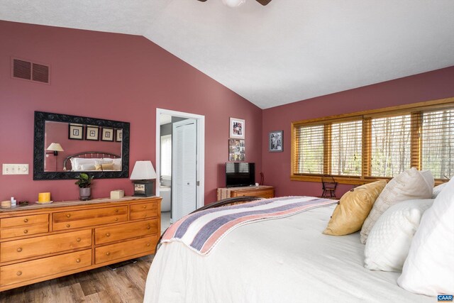 bedroom with visible vents, a ceiling fan, lofted ceiling, wood finished floors, and a closet