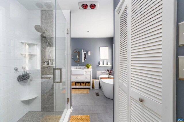 bathroom with a stall shower, visible vents, vanity, a freestanding tub, and a closet