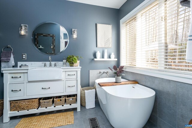 bathroom with visible vents, a soaking tub, vanity, and a healthy amount of sunlight