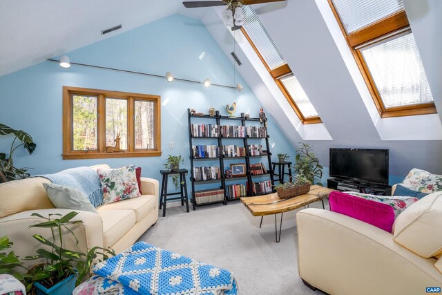 carpeted living area with vaulted ceiling with skylight, visible vents, and ceiling fan