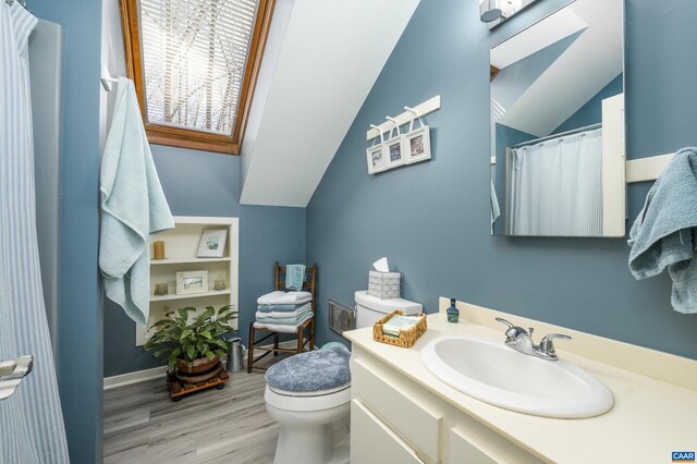 bathroom with vaulted ceiling, vanity, toilet, and wood finished floors