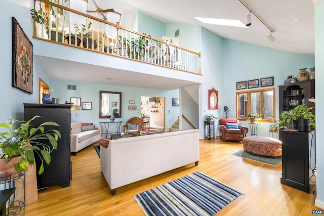 living area with a skylight, visible vents, stairway, wood finished floors, and track lighting