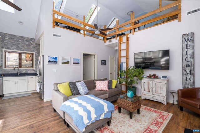 living area featuring a high ceiling, a skylight, wood finished floors, and visible vents