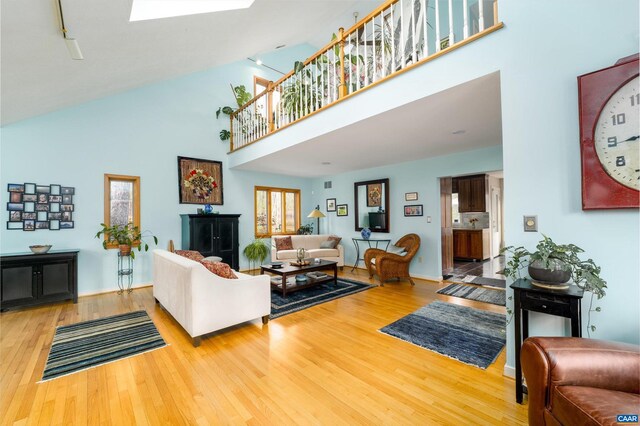 living room featuring a skylight, a towering ceiling, and wood finished floors