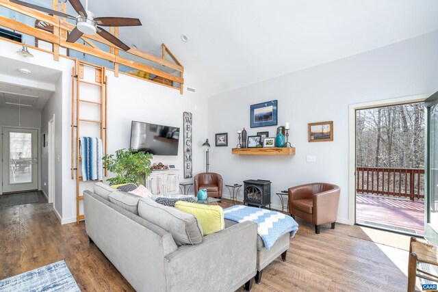 living area with a wood stove, attic access, a ceiling fan, and wood finished floors