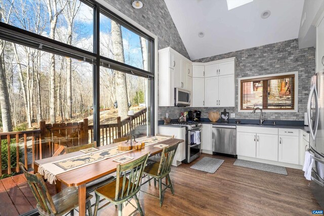 kitchen featuring dark wood finished floors, white cabinets, dark countertops, appliances with stainless steel finishes, and a sink